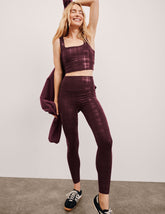 model wearing a plaid foil high-waisted midi leggings on a light gray background.