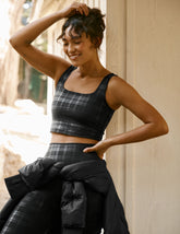 model wearing a black plaid foil printed square neck cropped tank top and matching leggings against a plain background.