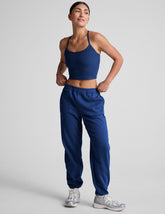 model wearing a blue cropped racerback tank and fleece joggers with pockets on a light gray background.