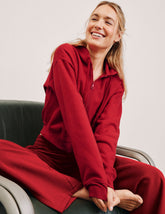 person wearing a red fleece zip-up jacket and red fleece pants against a plain background.