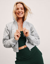 person wearing gray fleece zip-up jacket and green matching set against a plain background.