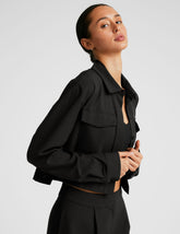 black cropped loose fitting jacket with a collar at neckline, hidden placket with button closure at center front, and front chest cargo pockets.