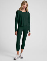 model wearing a green long sleeve and green high-waisted capri leggings on a plain background.