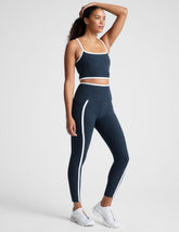 blue high-waisted midi length leggings with pockets and white piping.