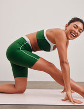 green high-waisted biker shorts with a 7" inseam, waistband colorblock panels, and contrast piping detail on leg.