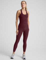 model wearing a red racerback tank top and leggings against a light gray background.