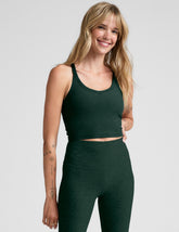 woman wearing a green v-neck racerback cropped tank and leggings on a light gray background.