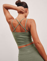 green waist length tank top with a v-neck and overlapping strap detail on back.