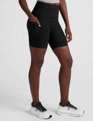 model wearing black 7" inseam biker shorts with pockets on a plain background.