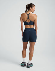 woman wearing a blue slim racerback bra and blue 3" biker shorts against a plain background.