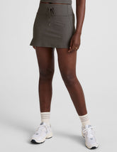 grey high-waisted mini athletic skirt with a drawstring at waistband and built-in shorts with pockets.