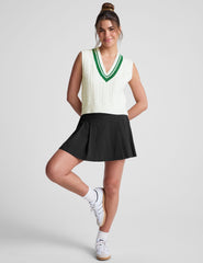 white relaxed fit cable knit vest with a neckline with contrast color stripe, rib hemband, neckline and armholes.