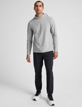 man wearing a gray hoodie and blue joggers on a plain background.