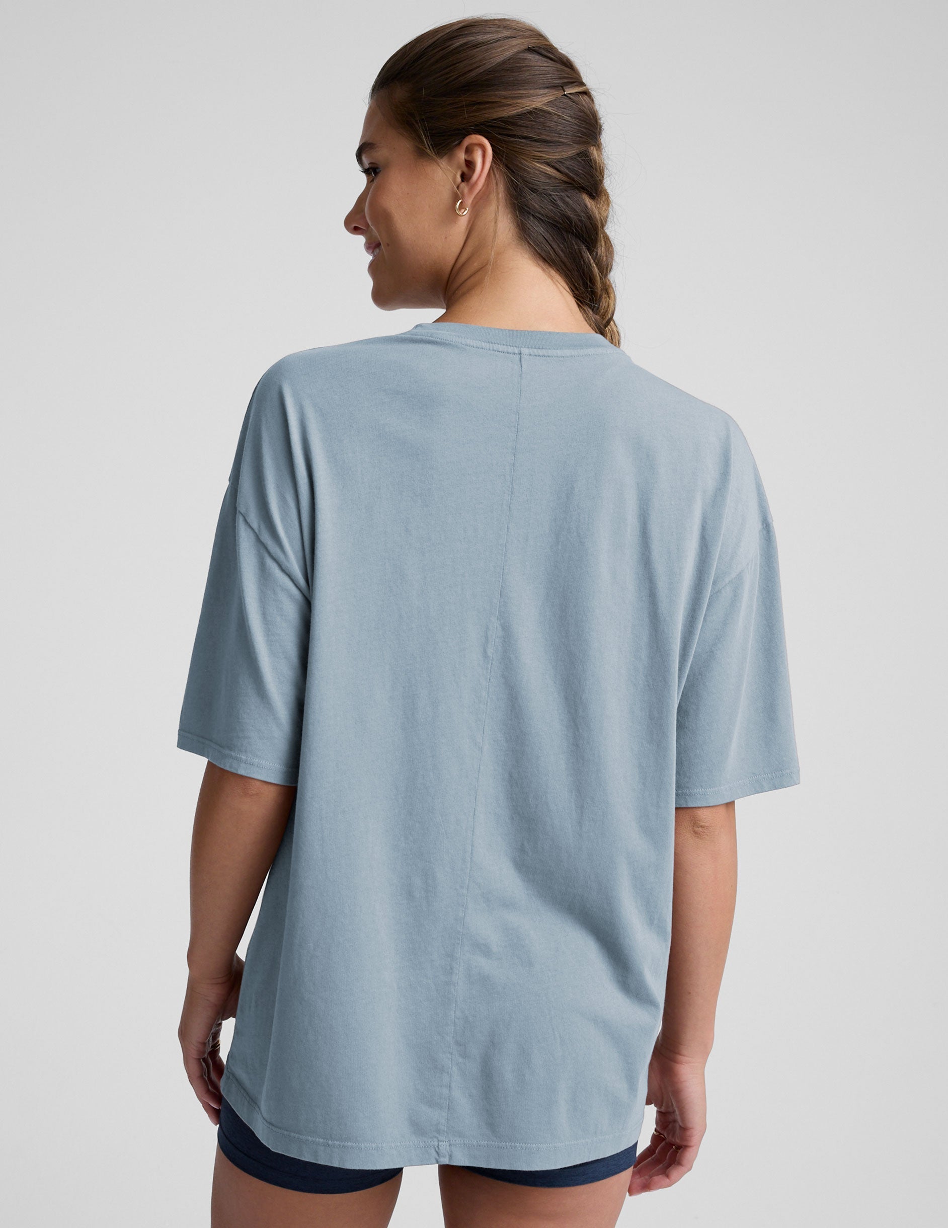 model wearing a light blue oversized cotton t-shirt and navy blue biker shorts against a plain background.