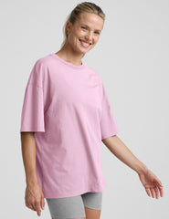 model wearing a pink oversized cotton t-shirt and grey biker shorts against a plain background.