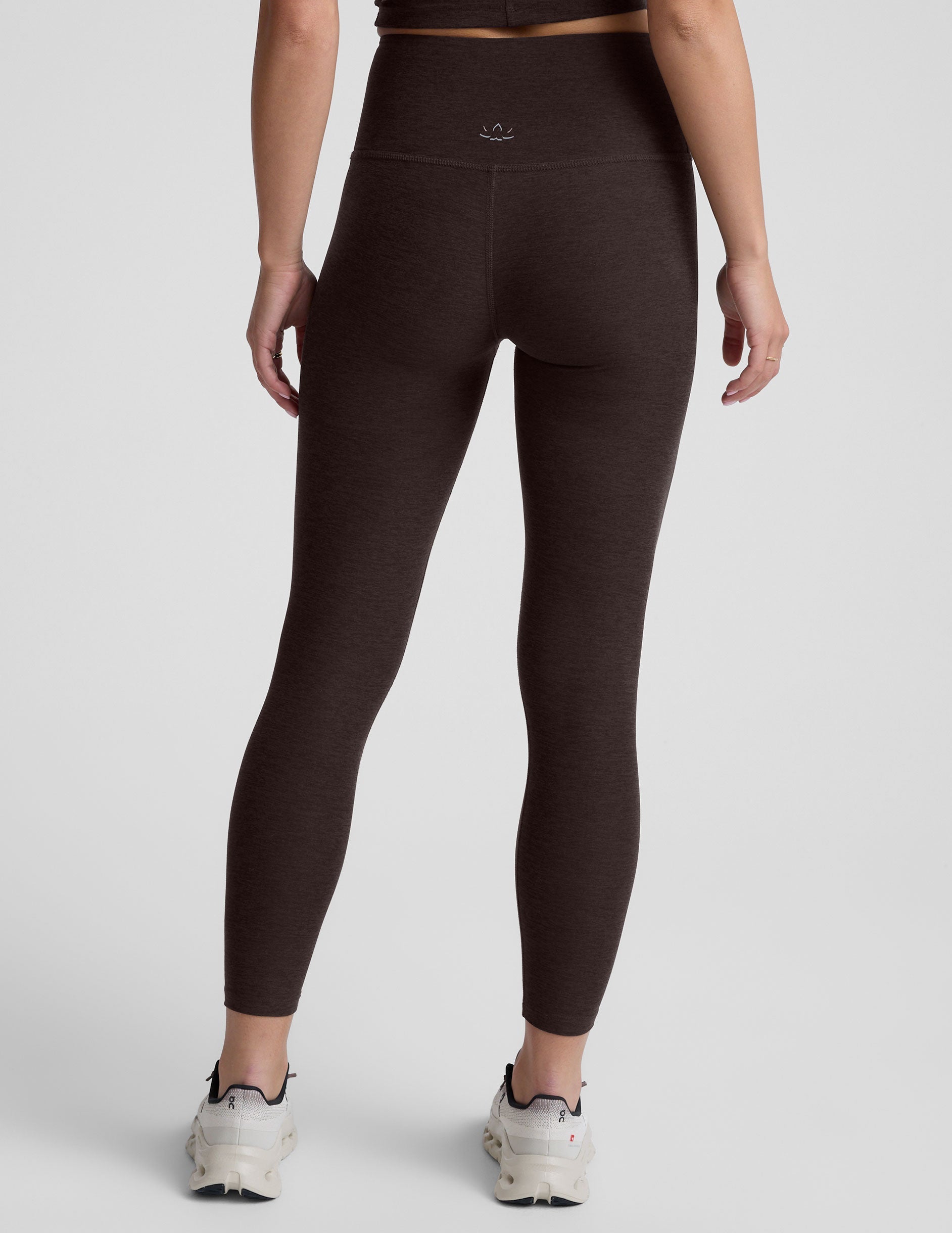 person wearing brown high-waisted midi leggings on a plain background.