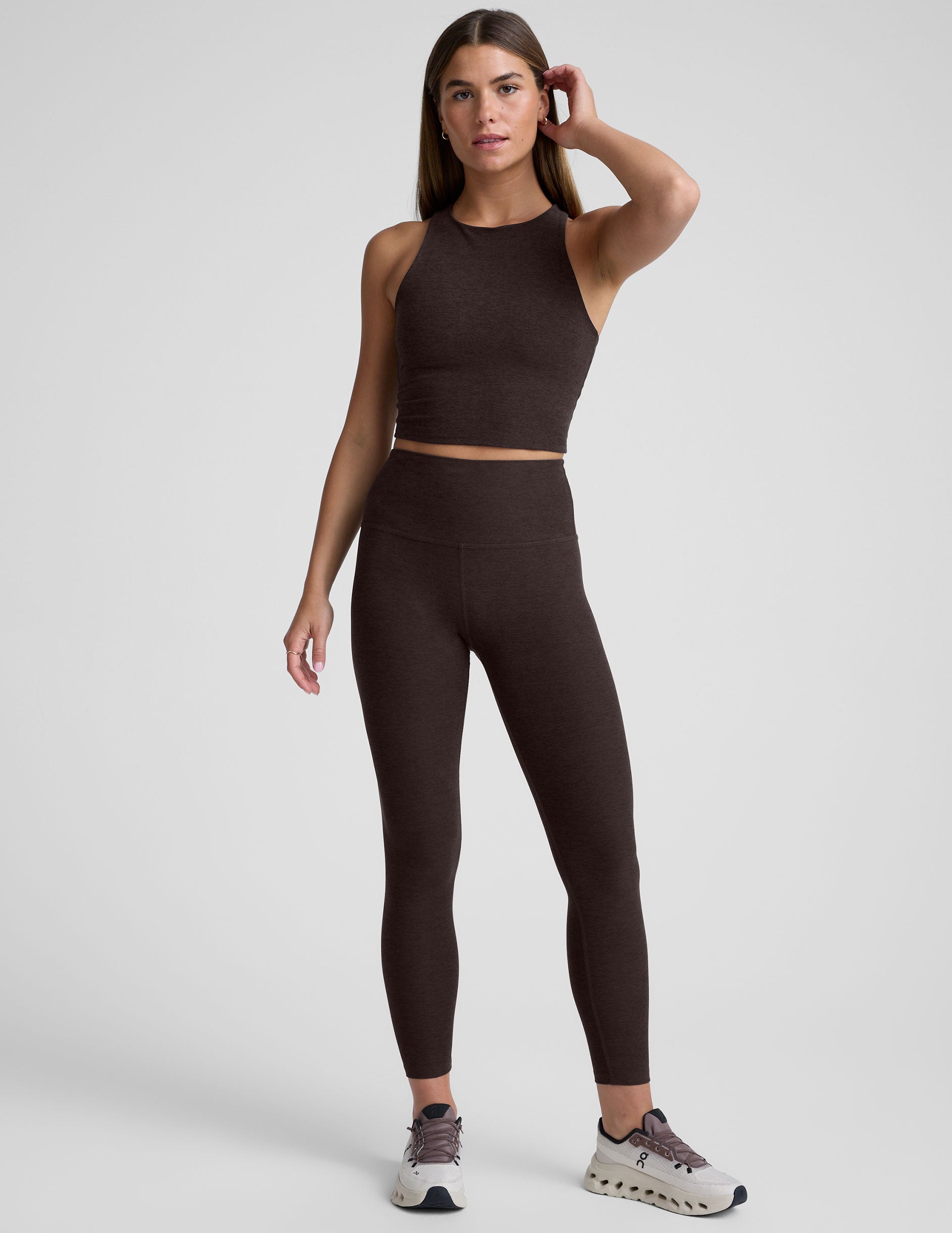 person wearing brown high-waisted midi leggings on a plain background.