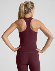 model wearing a red racerback tank top and leggings against a light gray background.