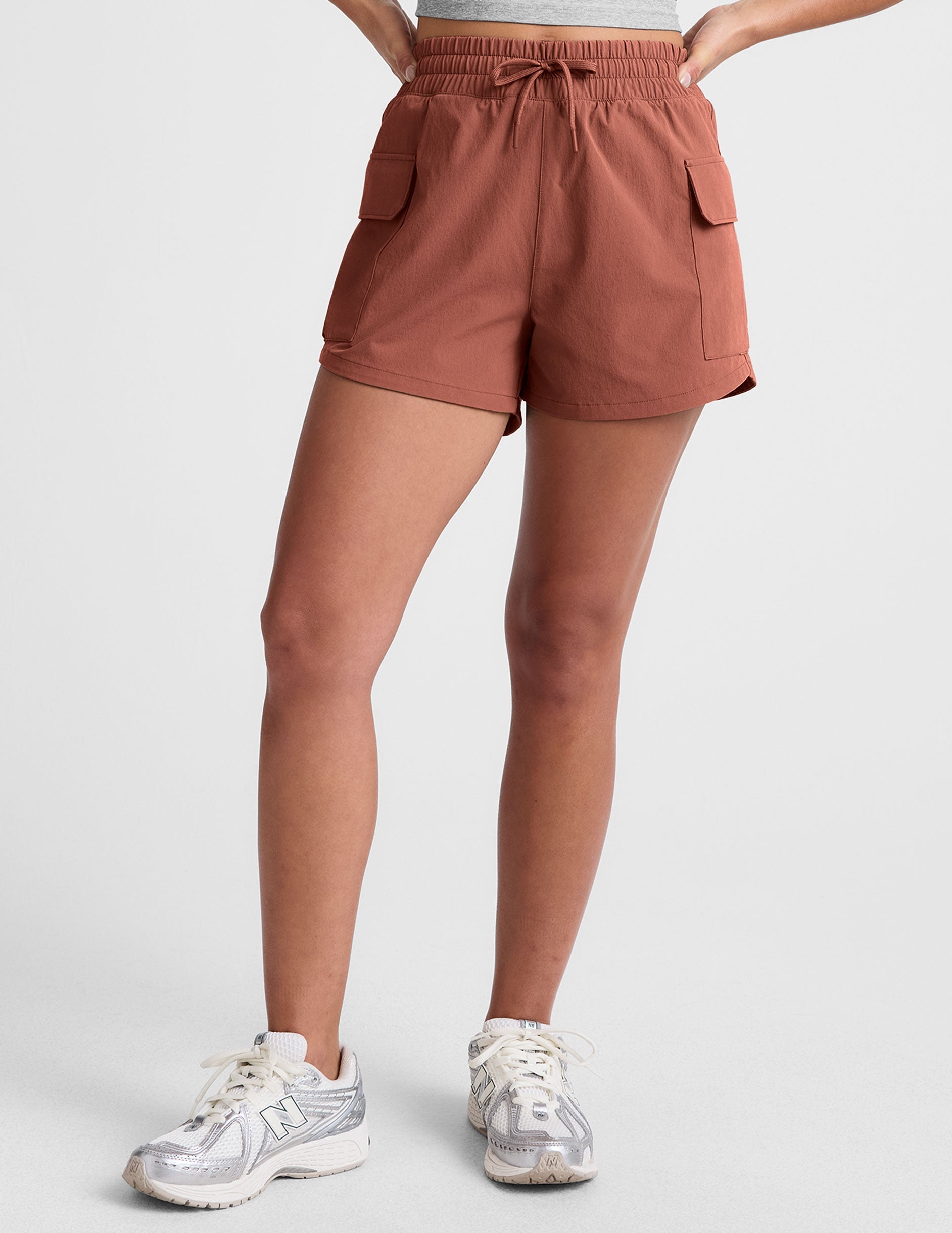 model wearing a gray tank top and auburn shorts on a plain background.