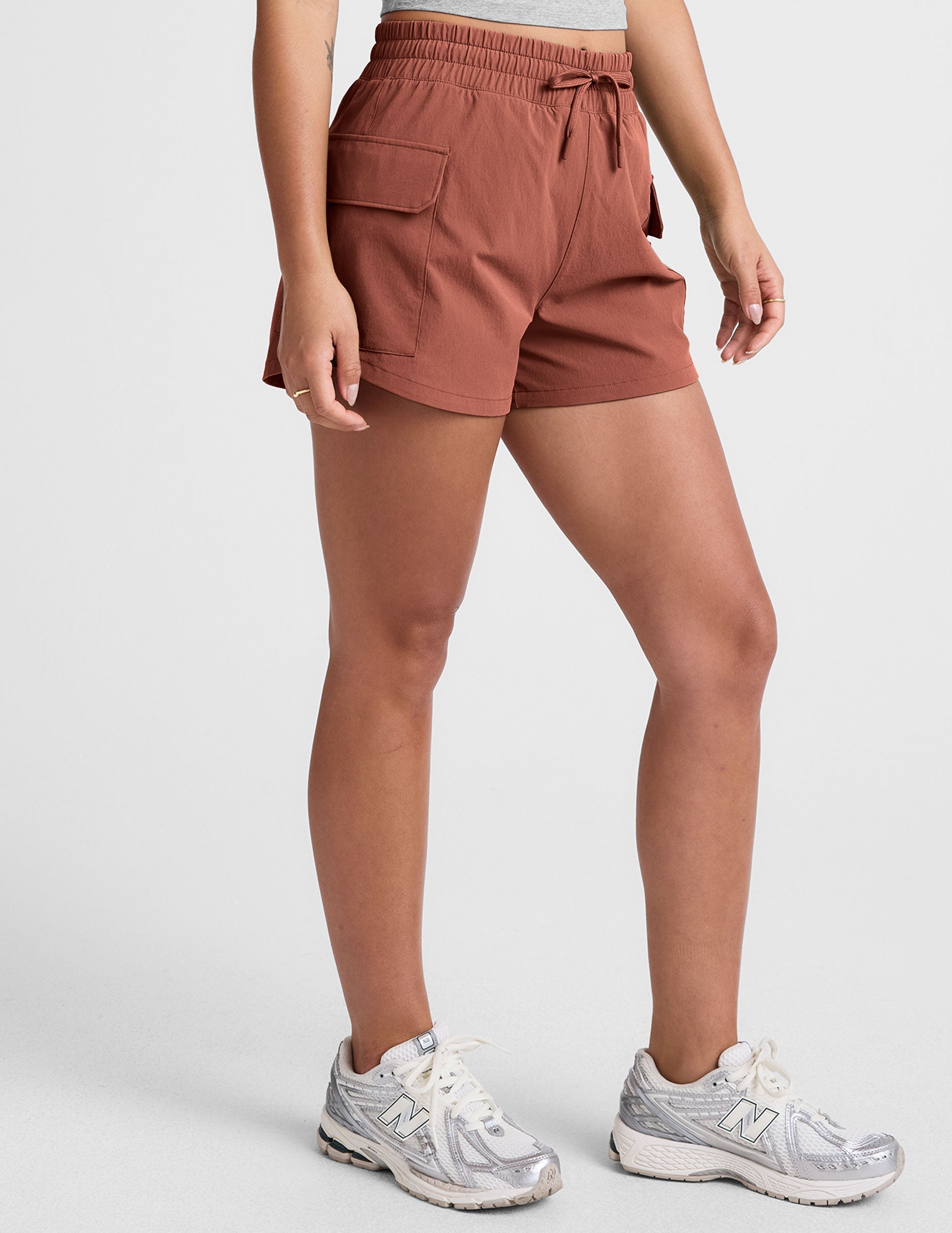 model wearing a gray tank top and auburn shorts on a plain background.