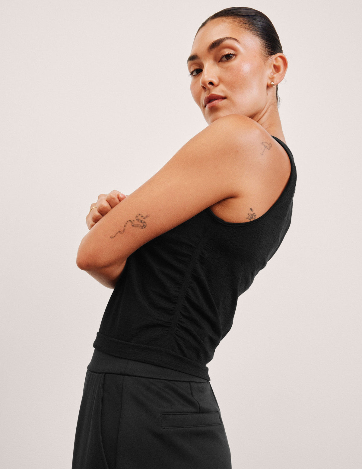 model wearing a scoop high neck racerback tank top against a plain background.