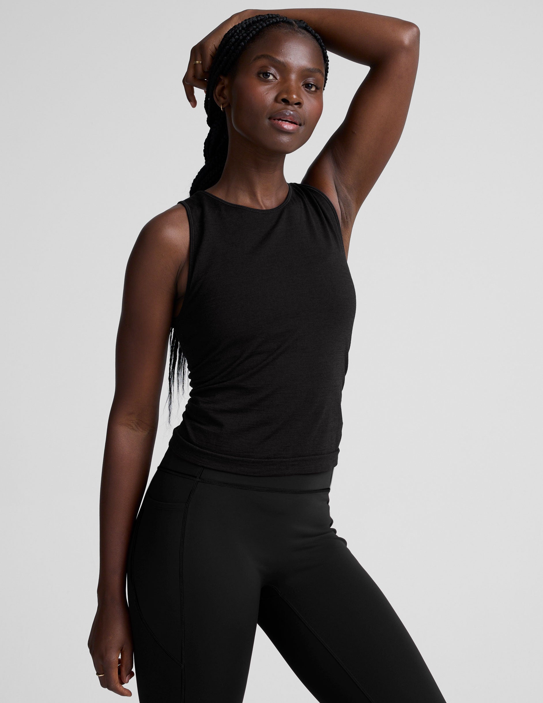 model wearing a scoop high neck racerback tank top against a plain background.